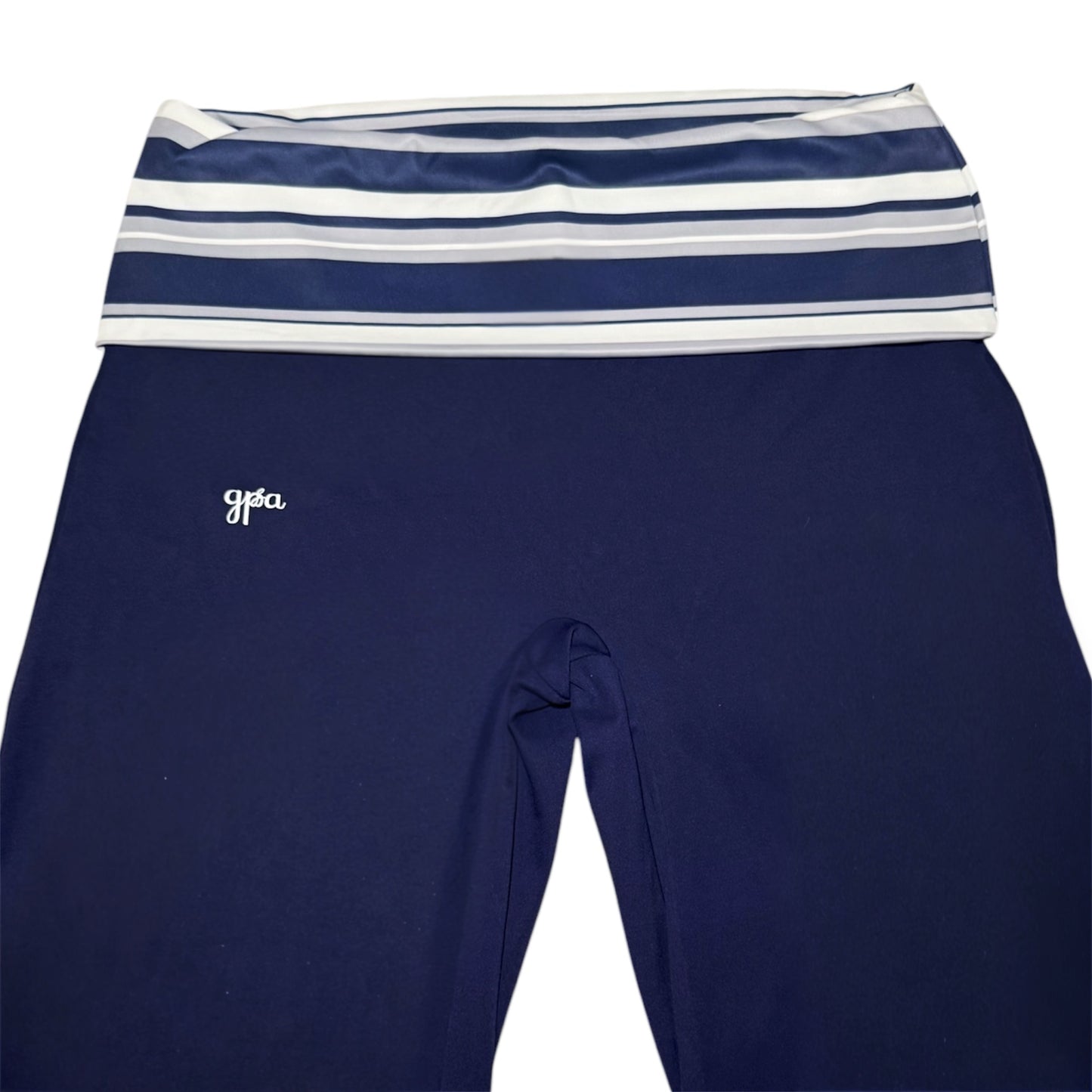 Navy blue leggings with a wide elastic waistband featuring navy, white, and light gray horizontal stripes, and a small white script logo on the left hip.